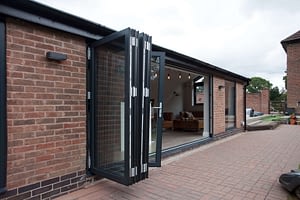 Aluminium grey bi-folding door showing the sashes stocked and inline. Highseal Manufacturing manufactures quality pvc and aluminium windows, doors and conservatories and are suppliers of composite doors to the trade, DIY, retail and commercial.