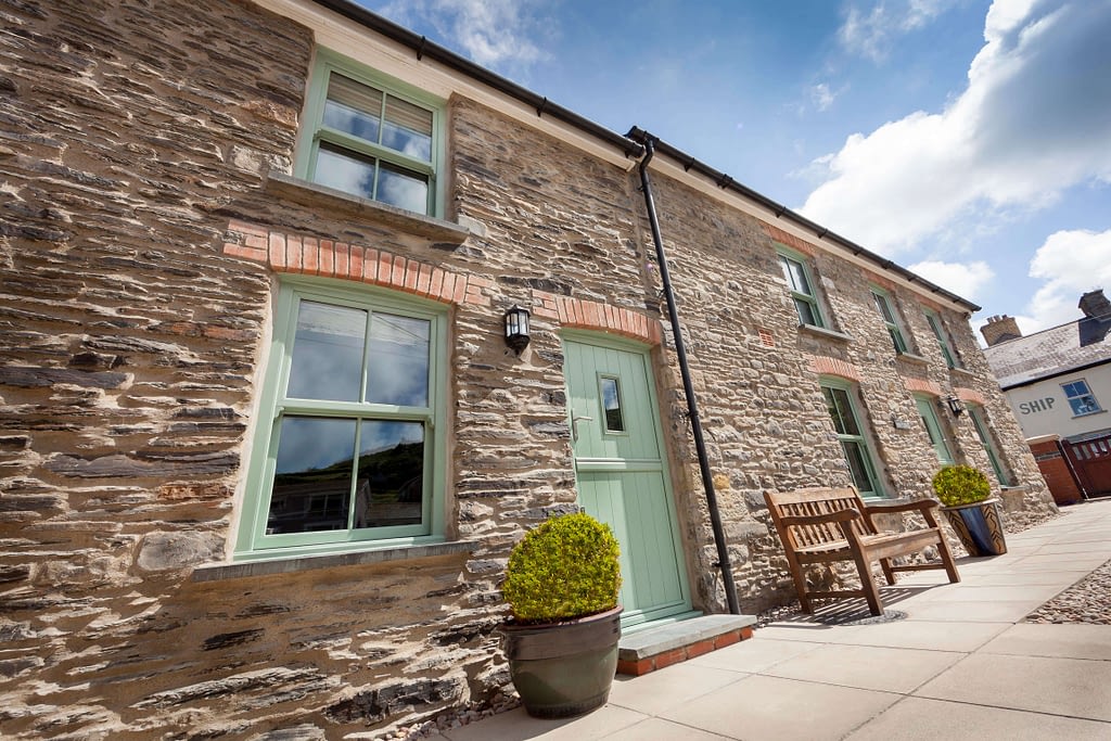 outside shot of cottage with chartwell green windows and doors Highseal Manufacturing Company, manufacturers windows, doors and conservatories. Highseal is a pvc and aluminium manufacturer which can supply nationwide to the trade, diy, commercial and retail. This image shows the chartwell green range Highseal can offer. Chartwell green vertical sliders and composite door. Highseal offers any RAL profile for their products.